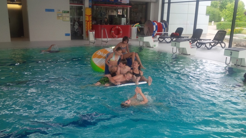Kinder schwimmen und spielen im Wasser des Hallenbades
